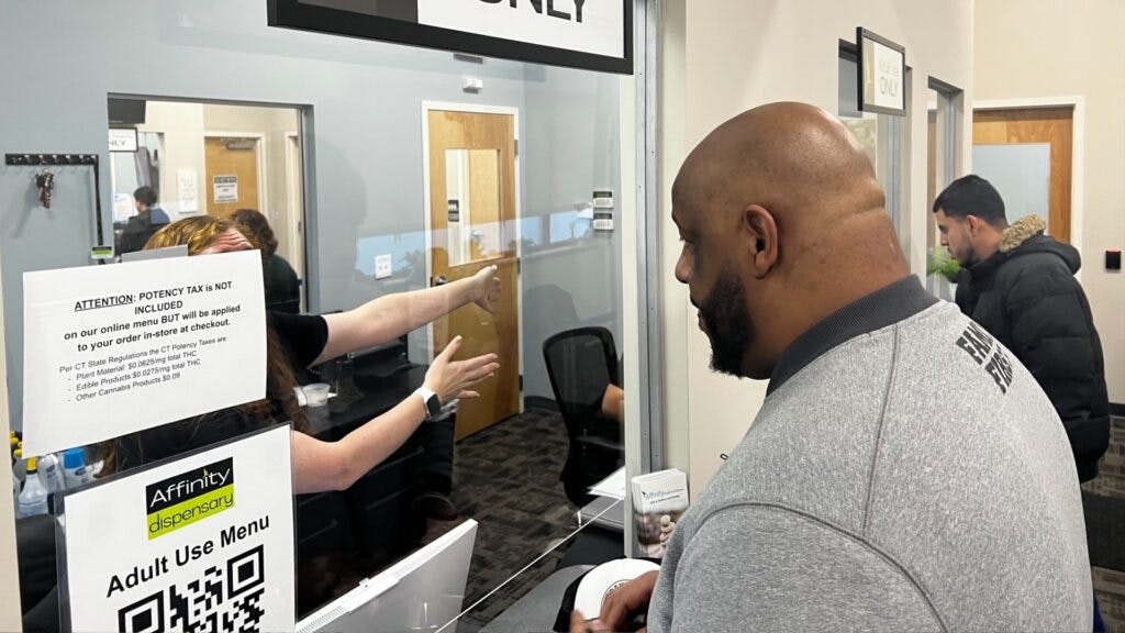 One of Connecticut’s first-time adult-use cannabis buyers takes directions from a budtender at Affinity Dispensary. Vic (right) is a professional security guard for celebrities who said legal stores won’t shut down Connecticut’s illicit market, but the option will benefit those who fear for their safety when buying from unlicensed suppliers. (Mikhail Harrison / Leafly)